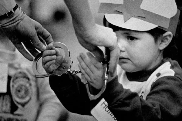 A police officer handcuffs a small child during a demonstration.