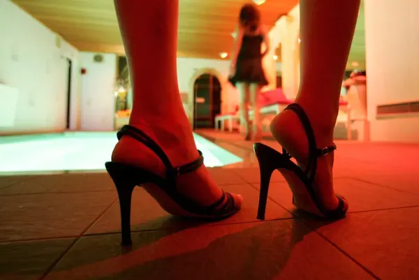 A zoom in on a photo of a woman in heels in red lighting, so as to symbolize sex work or something
