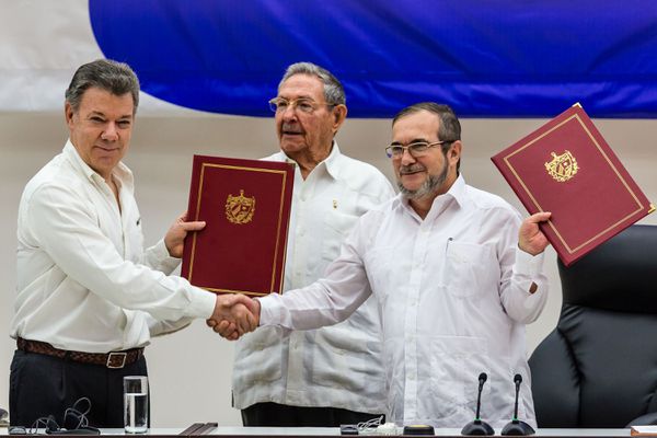 Colombian President Juan Manuel Santos, left, and Timoleón Jiménez, right, the top leader of the Revolutionary Armed Forces of Colombia, exchange pacts while Cuban President Raúl Castro witnesses in Havana.